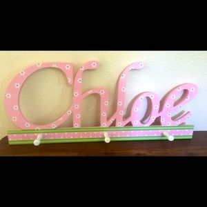 Pink “Chloe” custom name wall hanging with pegs to hang items.